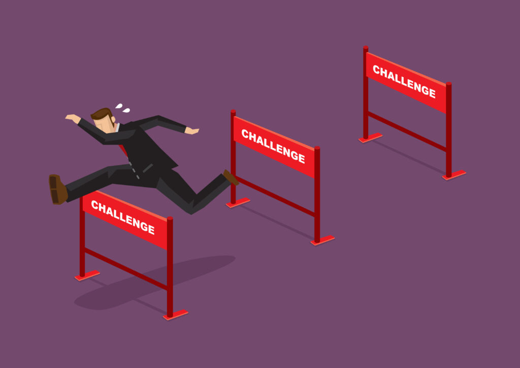 Image of a businessman jumping over series of hurdles with text Challenge on them.