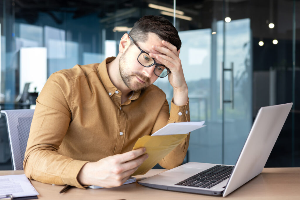 Image of a Shocked businessman sitting at his laptop.